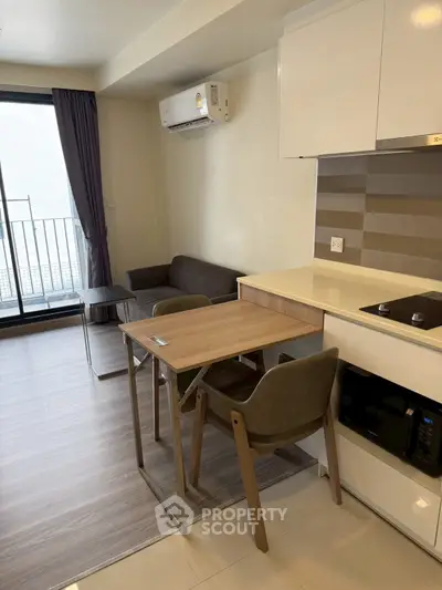 Modern compact living room with kitchen area and balcony access in a stylish apartment.