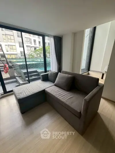 Modern living room with pool view and stylish gray sofa in luxury apartment.