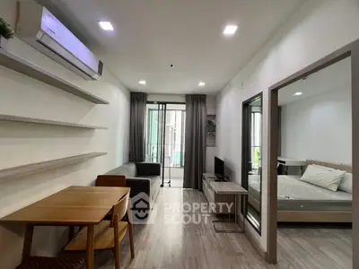 Modern apartment interior with open living room and bedroom, featuring sleek furniture and natural light.