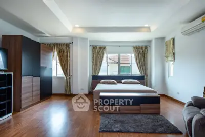 Spacious modern bedroom with wooden flooring and large windows for natural light.