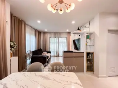 Modern living room with elegant decor and open layout, featuring a stylish chandelier and cozy seating area.