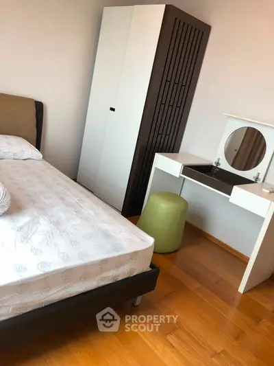 Modern bedroom with stylish furniture and wooden flooring, featuring a sleek wardrobe and vanity desk.