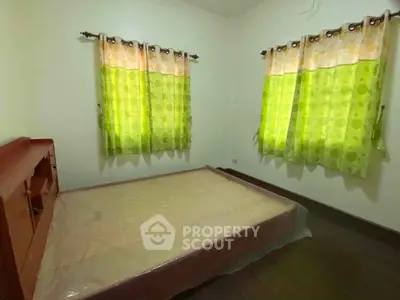 Cozy bedroom with green curtains and wooden flooring, perfect for a restful retreat.