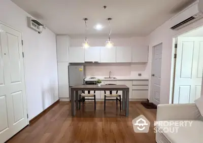 Modern kitchen with sleek white cabinets and cozy dining area in open layout apartment.