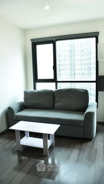 Modern living room with sleek gray sofa and city view window, perfect for urban living.