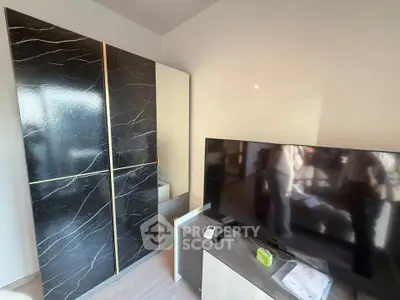 Modern bedroom with sleek black wardrobe and flat-screen TV, perfect for contemporary living.