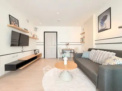 Modern living room with stylish decor, featuring a cozy sofa, wall-mounted TV, and elegant shelving.