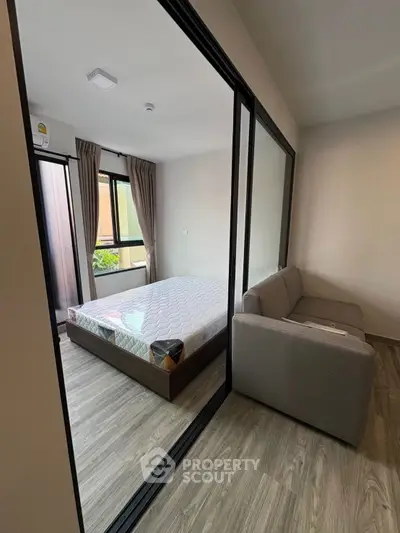 Modern bedroom with glass partition and cozy sofa in stylish apartment