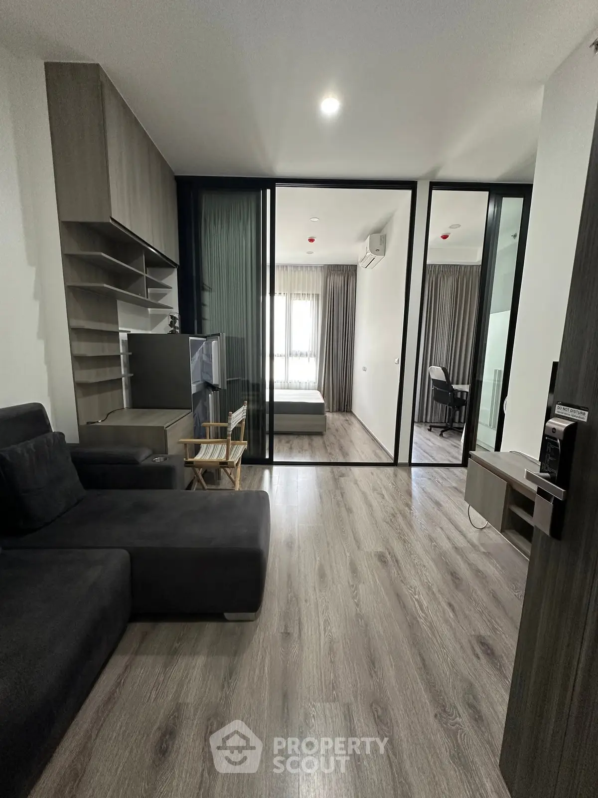 Modern living room with sleek design and glass partition leading to bedroom