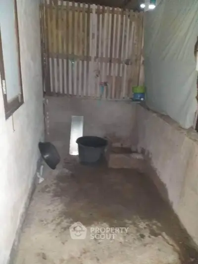 Basic unfinished room with concrete walls and minimal furnishings.