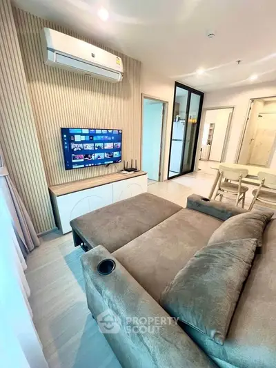 Modern living room with stylish decor, featuring a cozy sofa, wall-mounted TV, and elegant dining area.