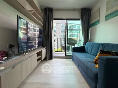Modern living room with balcony view, stylish furniture, and large TV in a cozy apartment setting.