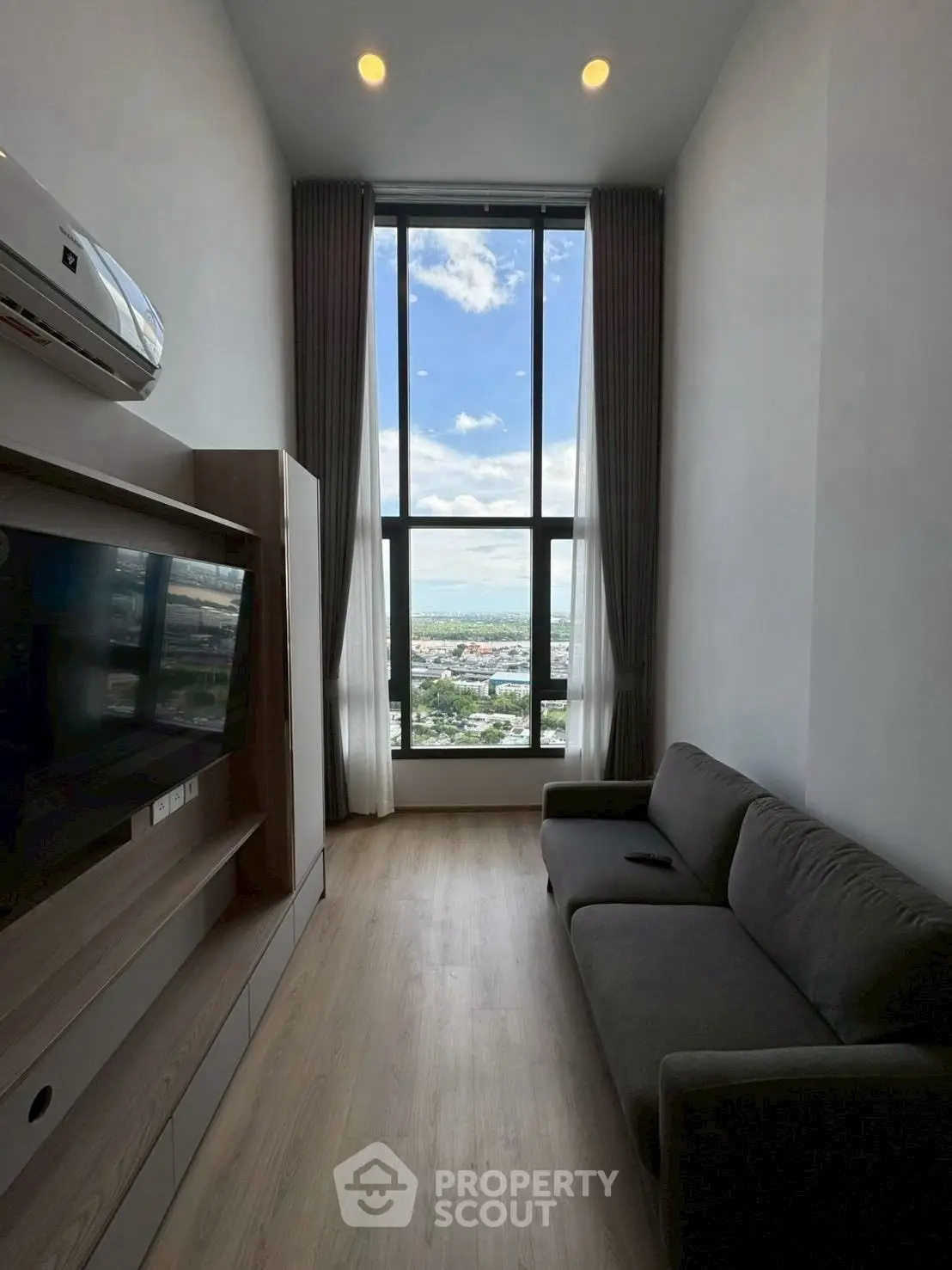 Modern living room with floor-to-ceiling window offering stunning city view
