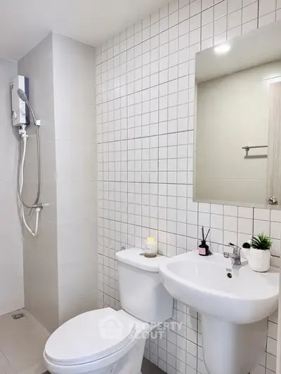 Modern bathroom with sleek white fixtures and tiled walls, featuring a shower and elegant decor.