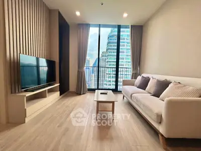 Modern living room with large windows and city view, featuring a sleek TV setup and comfortable sofa.
