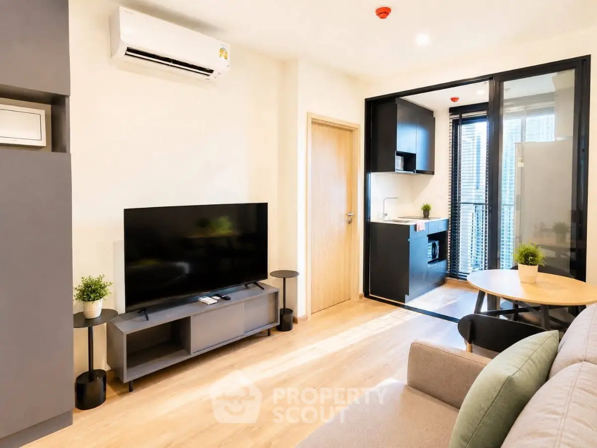 Modern living room with open kitchen, featuring sleek furniture and natural light.