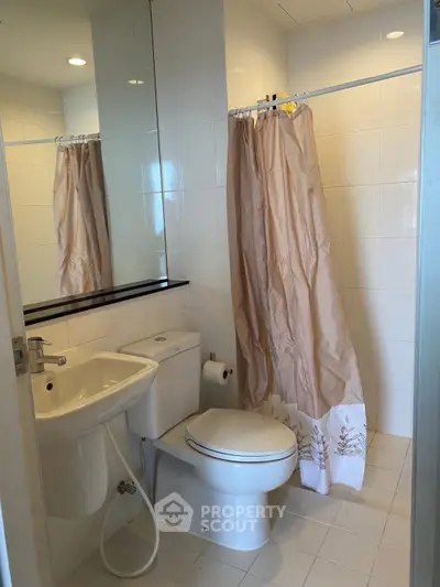 Modern bathroom with sleek fixtures and shower curtain in a bright, tiled space.