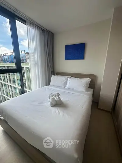 Modern bedroom with large window and stylish decor in a high-rise apartment.