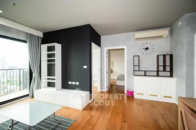 Modern living room with wooden flooring, large window, and stylish furniture in a high-rise apartment.