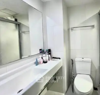 Modern bathroom with sleek fixtures and a spacious mirror, perfect for contemporary living.