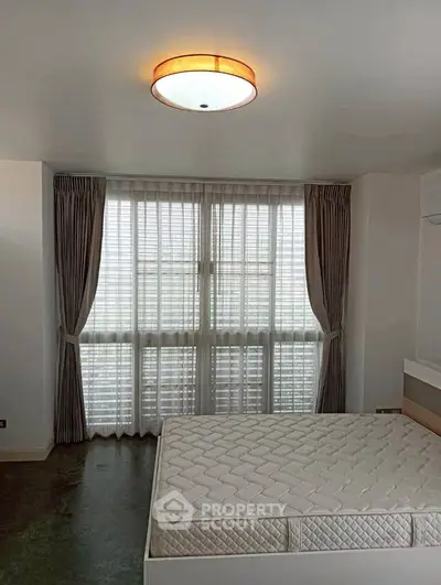 Spacious bedroom with large window and modern lighting