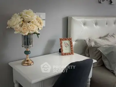 Elegant bedroom corner with plush headboard and decorative floral arrangement.