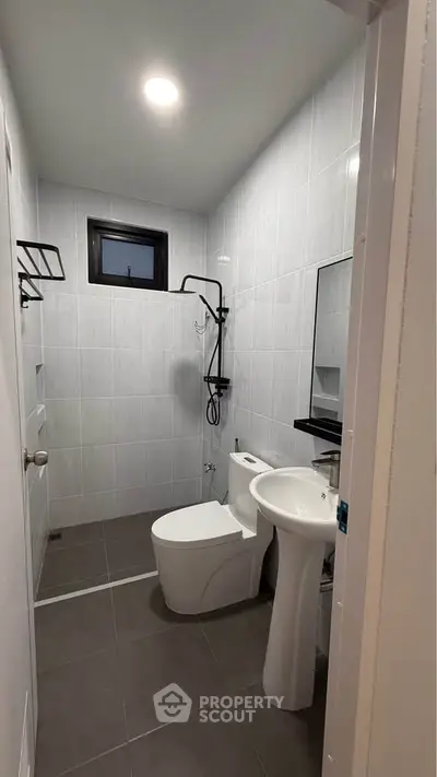 Modern bathroom with sleek fixtures and minimalist design, featuring a shower, toilet, and sink.