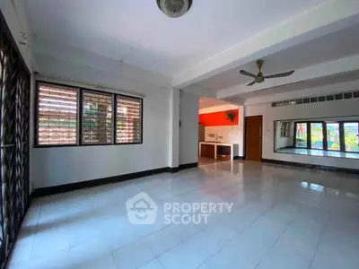 Spacious living room with large windows and ceiling fan in modern apartment