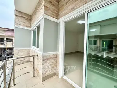Modern balcony with sleek railing and sliding glass doors in a contemporary building.