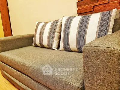 Cozy living room with stylish gray sofa and striped cushions, perfect for relaxation.