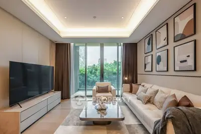 Luxurious modern living room with large TV and stylish decor, overlooking a scenic view through glass doors.