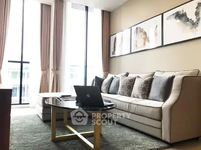 Modern living room with stylish sofa, elegant decor, and large windows for natural light.