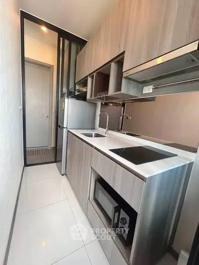 Modern compact kitchen with sleek cabinetry and built-in appliances in a stylish apartment.