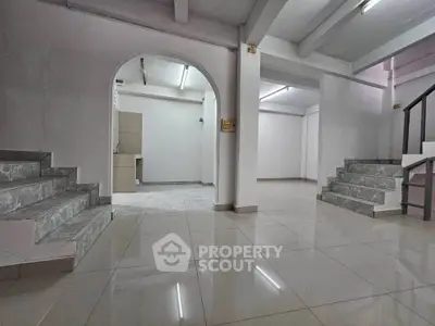 Spacious interior with tiled floors and modern staircase, ideal for versatile living or office space.