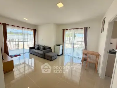 Spacious living room with large windows and balcony access, featuring modern furniture and abundant natural light.