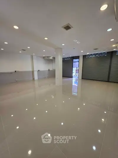 Spacious commercial space with glossy tiled floors and ample lighting, ideal for retail or office use.
