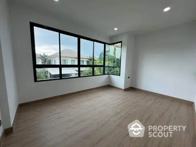 Spacious corner unit with large windows and wooden flooring offering a serene view.