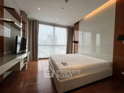 Luxurious bedroom with modern design and city view, featuring a sleek TV setup and elegant wooden flooring.
