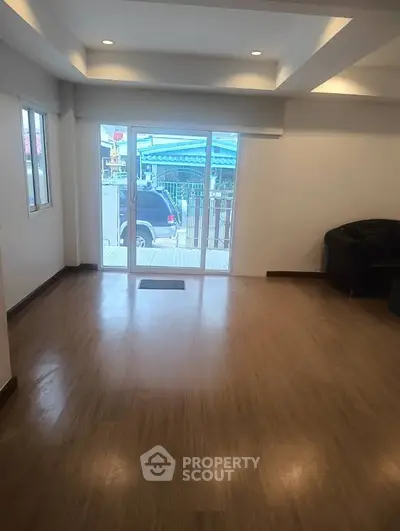 Spacious living room with wooden flooring and large windows for natural light.