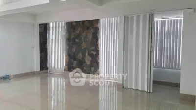 Spacious modern living room with large windows and stylish stone accent wall.