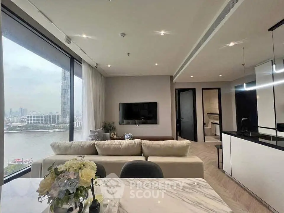 Luxurious living room with stunning river view and modern open kitchen layout.