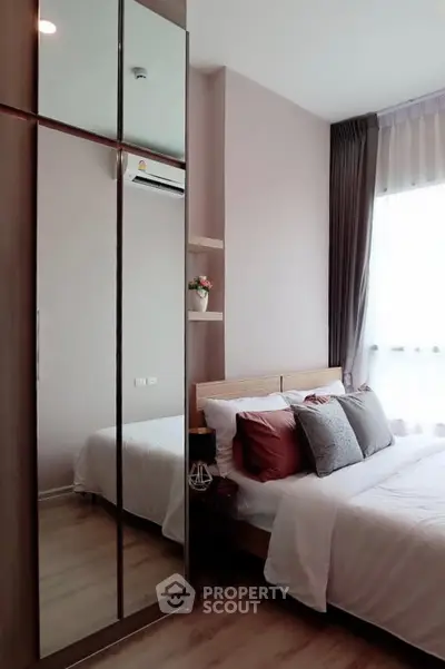 Modern bedroom with stylish decor and large mirrored wardrobe in a cozy apartment.