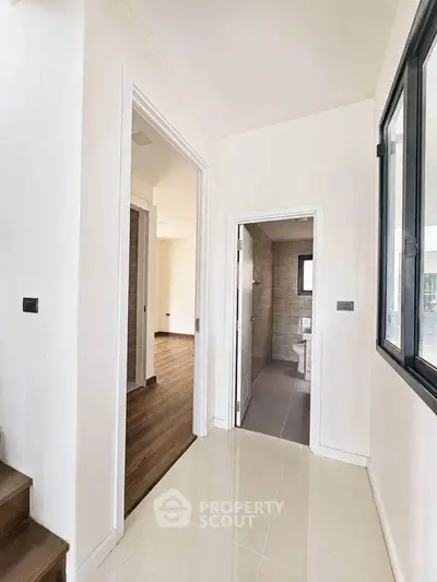 Bright hallway with modern bathroom and wooden flooring, ideal for contemporary living.