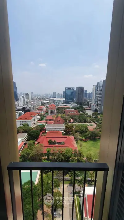 Stunning cityscape view from a high-rise balcony overlooking urban skyline and lush greenery.
