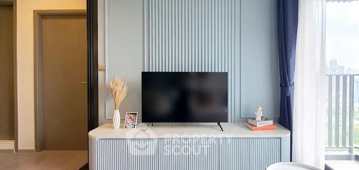 Modern living room with TV and elegant decor, featuring a city view from the balcony.
