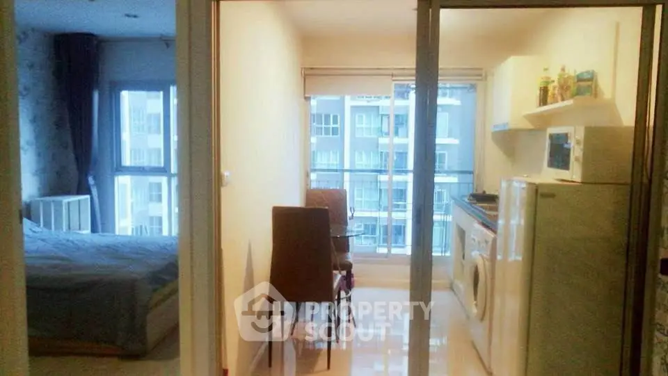 Modern apartment interior with bedroom and kitchen, featuring large windows and natural light.