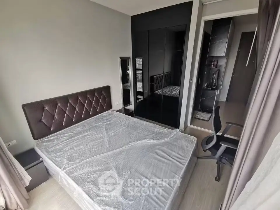 Modern bedroom with sleek design, featuring a large bed, mirrored wardrobe, and office chair for a stylish living space.