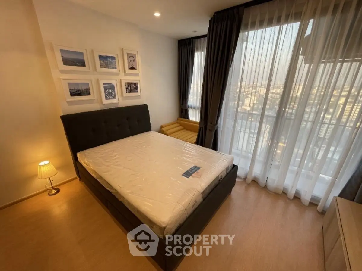 Modern bedroom with city view, featuring a stylish bed and large windows for natural light.