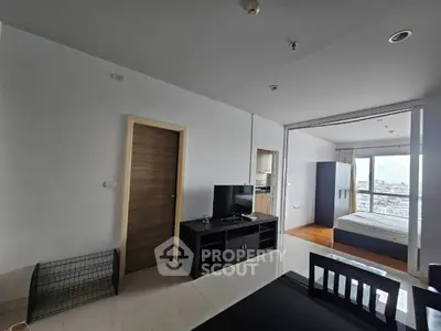 Modern apartment interior with open living area and bedroom, featuring sleek furniture and city view.