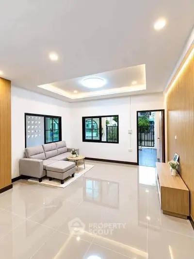 Spacious modern living room with elegant ceiling lights and sleek tile flooring.